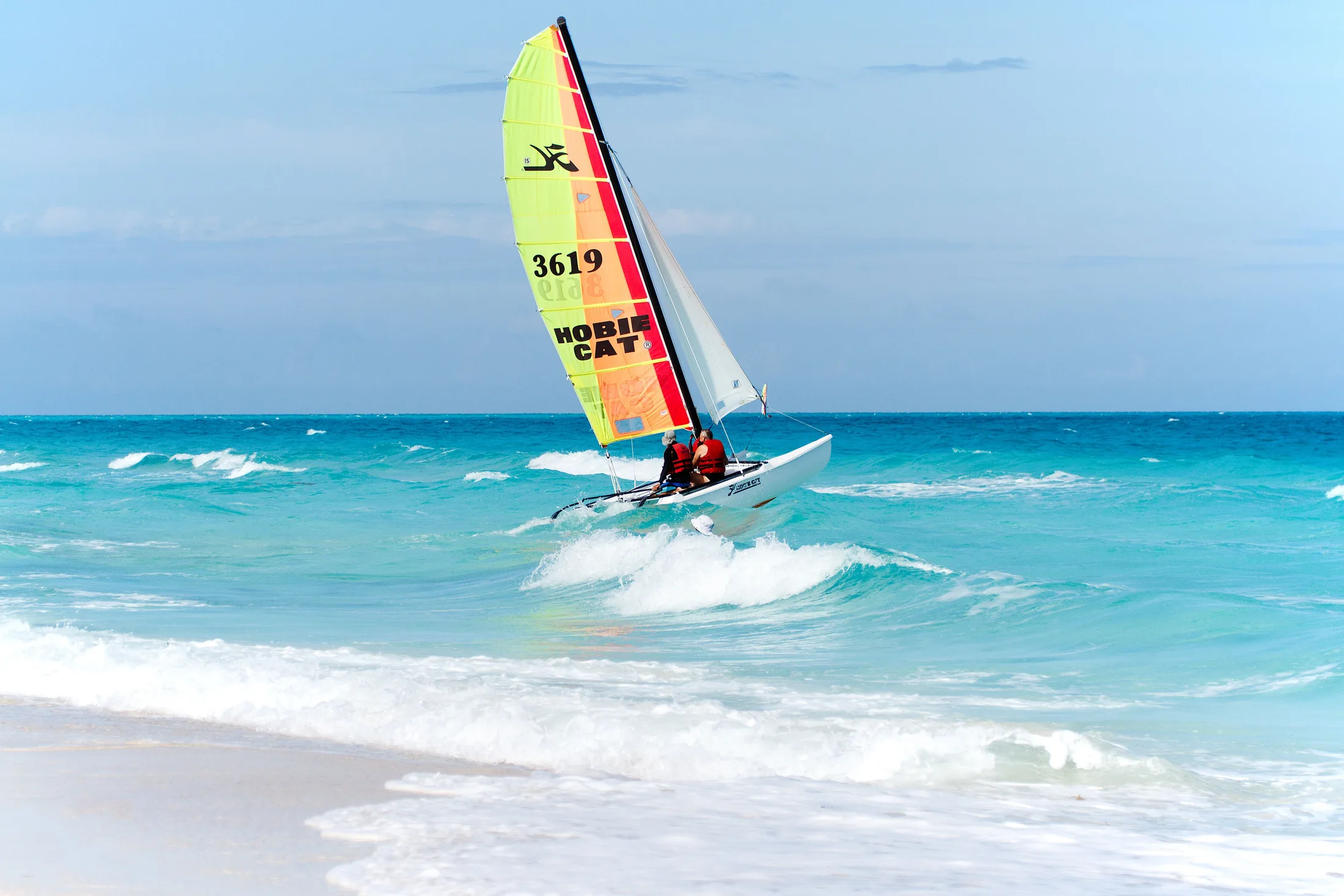 A small catamaran sailing across open blue water