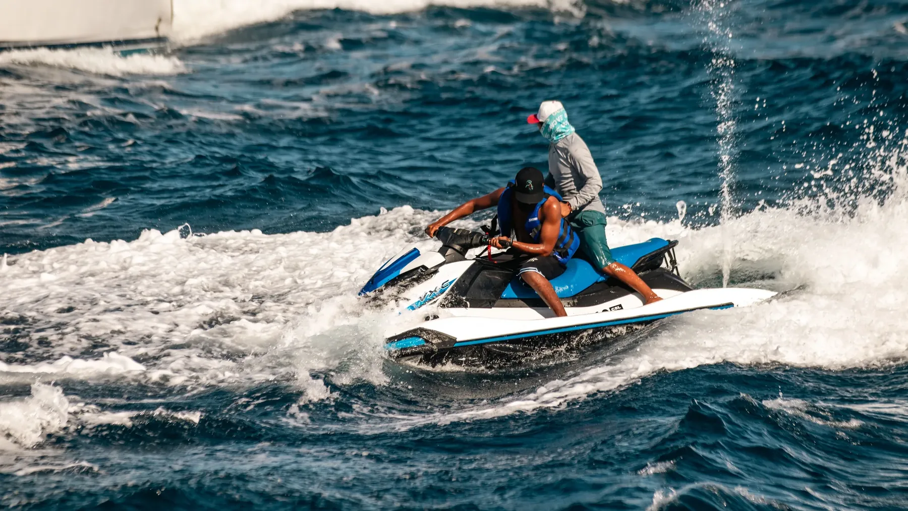 Two riders steering a jet ski across open water