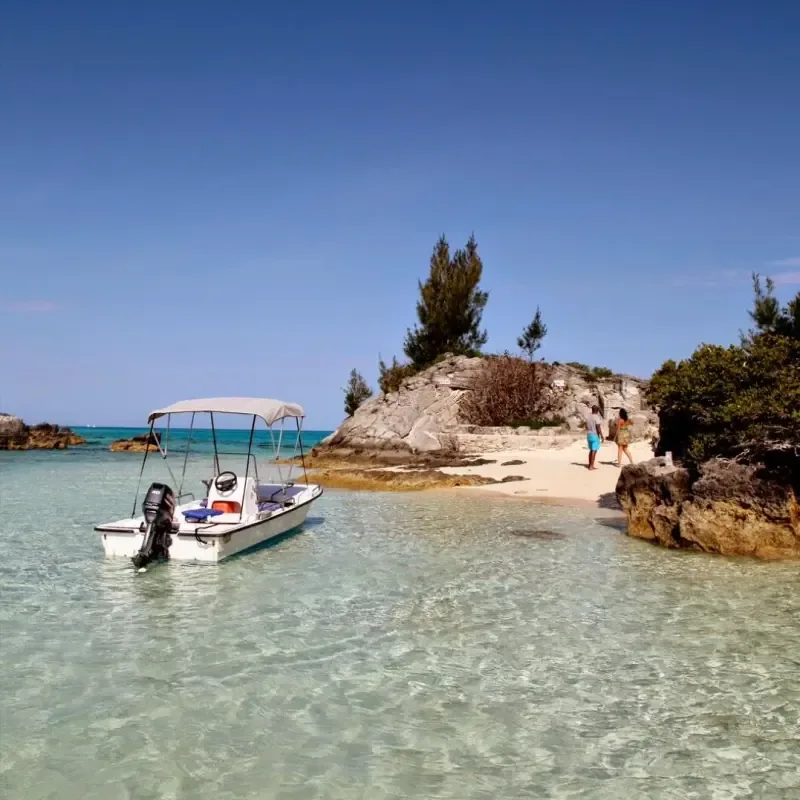 H2O Sports' open motorboat beside a rocky Bermuda shoreline